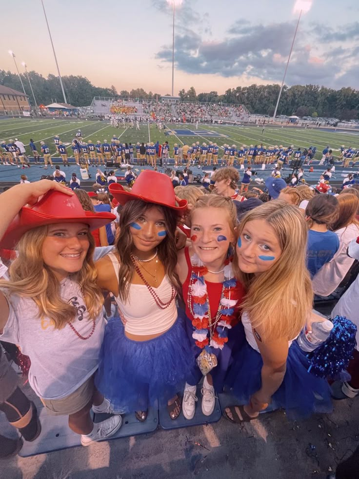 three girls wearing red hats and blue tutus at a football game in the sun