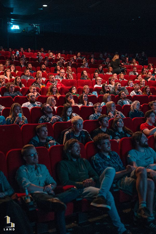 people sitting in red chairs watching something on the screen