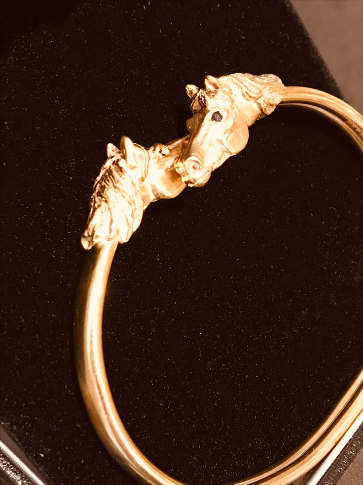 18 carat gold with sapphire eyes. The heads are done in a satin finish, with the manes and nostrils highlighted in a shiny finish. The shank is also highly polished. The bangle fits over the wrist, not over the hand and the shank acts like a spring to open and close sideways. (Fitting instruction comes with the bangle in its box). This bangle appeals to passionate horse lovers, and is suitable for everyday wear and for that special occasion! I can make a larger shank (at an extra cost), but it is intended to be a snug fit. Classic Formal Jewelry With Horse Design, Adjustable Formal Bangle With Shiny Finish, Adjustable Shiny Finish Bangle For Formal Occasions, Adjustable Shiny Bangle For Formal Occasions, Formal Adjustable Hallmarked Bangle, Classic Gold Jewelry With Horse Design, Elegant Round Jewelry With Horse Design, Elegant Gold Jewelry With Horse Design, Elegant Yellow Gold Jewelry With Horse Design