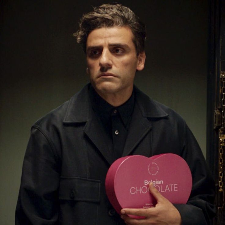 a man holding a heart shaped box with the words chocolate in front of his face