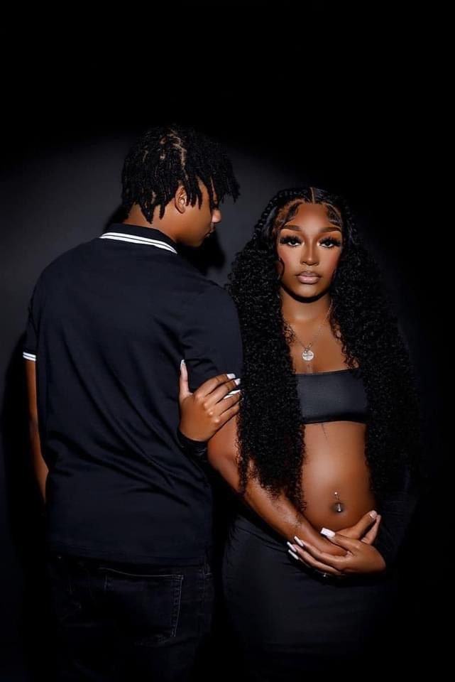 a man and woman standing next to each other in front of a black background with long hair