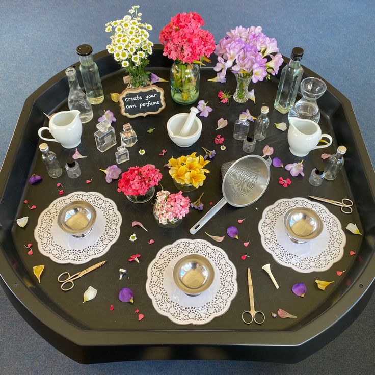 a black tray topped with dishes and flowers