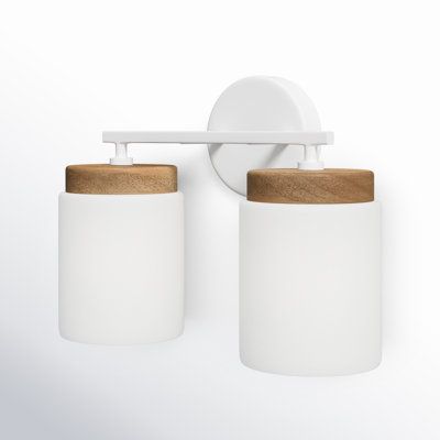 two white jars with wooden lids are hanging on the wall next to a toothbrush holder