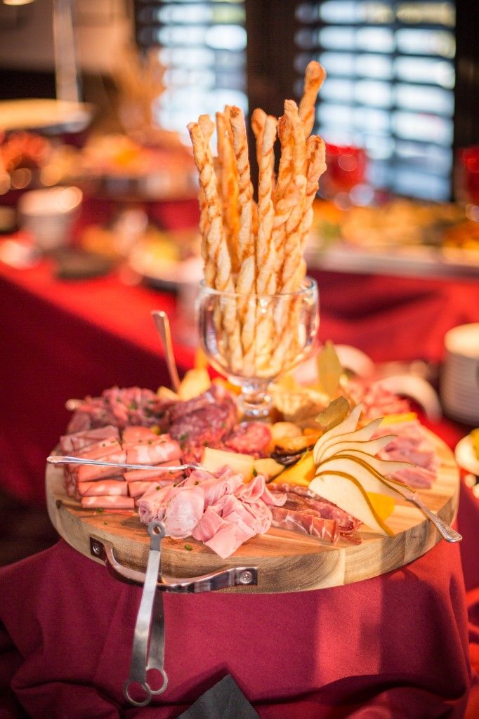 an assortment of meats and cheeses on a platter with utensils