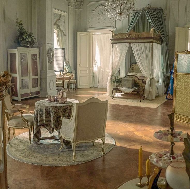 an elegant bedroom with chandelier, bed, and table in it's center