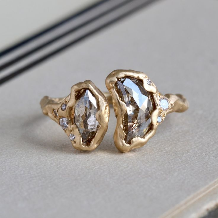 two gold rings sitting on top of a white table next to each other with diamonds in them