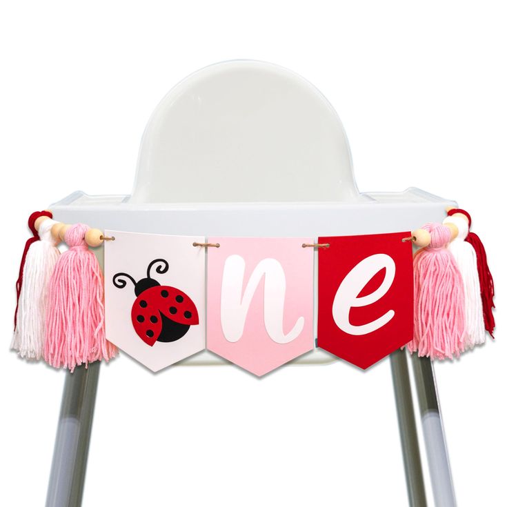 a white chair with pink tassels and ladybug banner