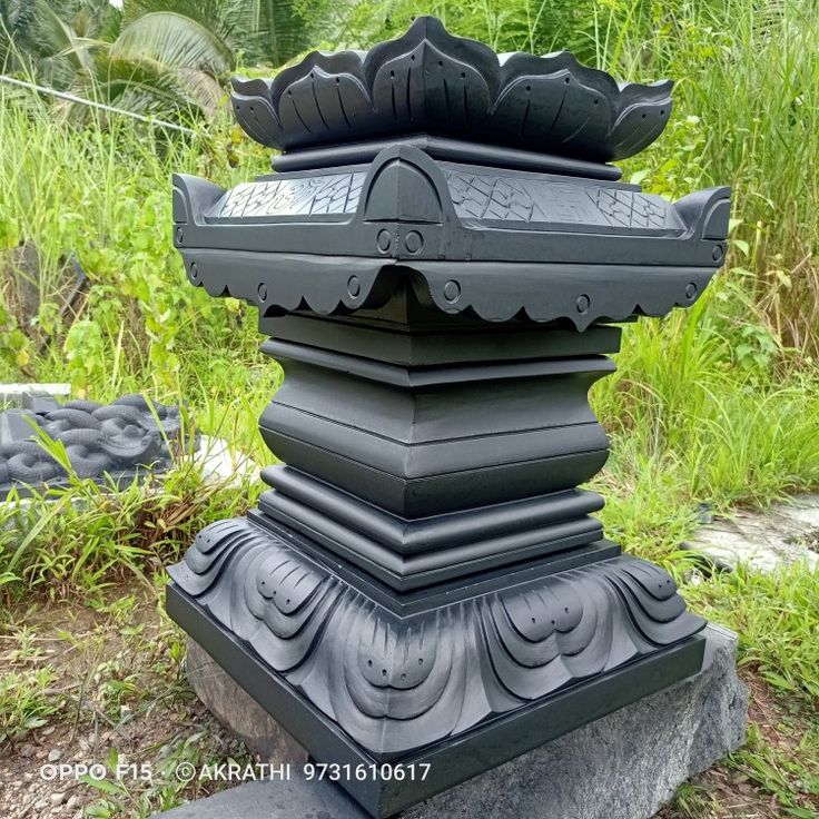 a large black statue sitting on top of a lush green field