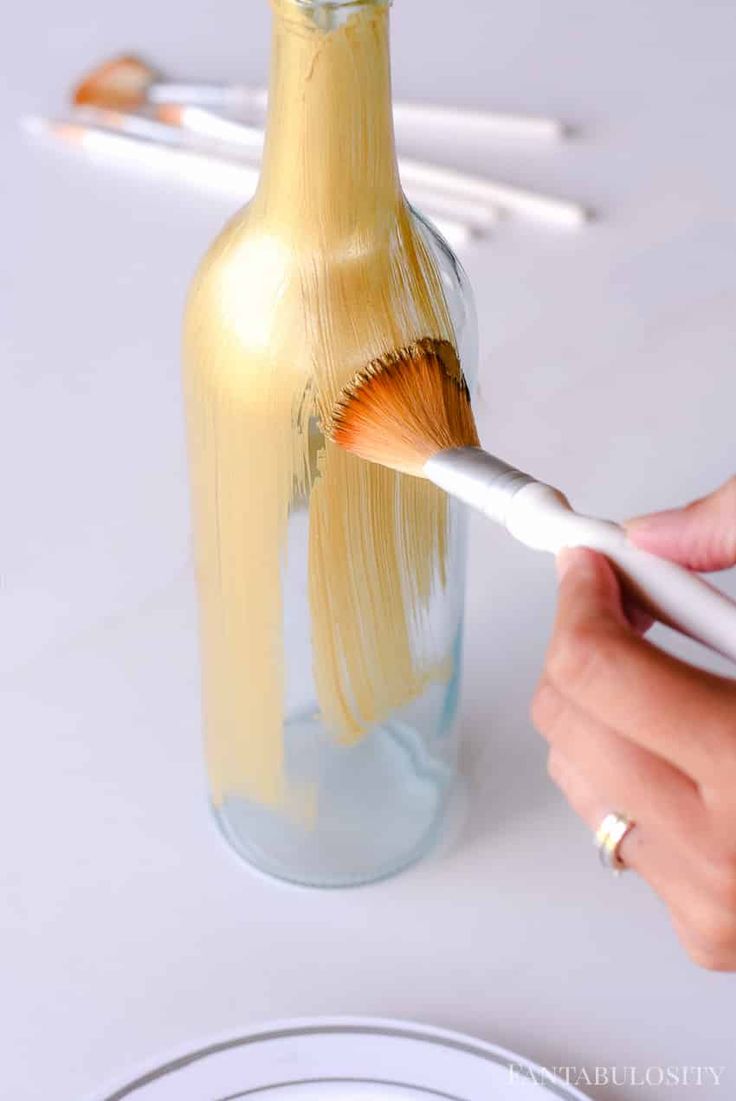 a person is painting a bottle with paintbrushes