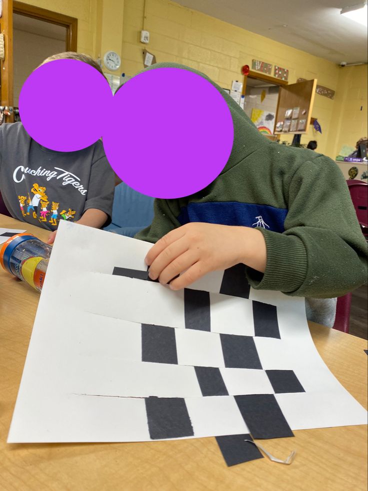 a child making a checkerboard pattern out of construction paper with purple circles over it