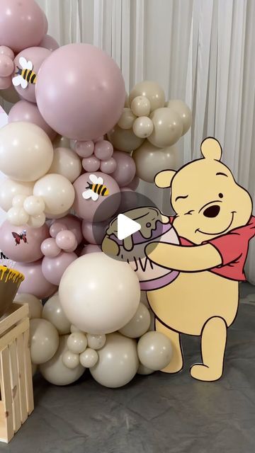 winnie the pooh balloon arch with honeybees, balloons and other items on display