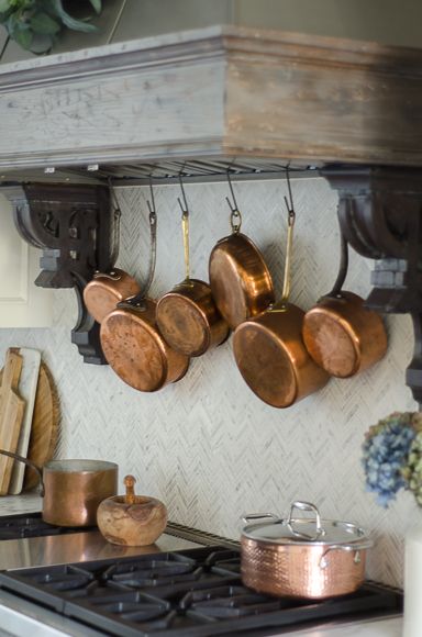 pots and pans are hanging on the wall above the stove