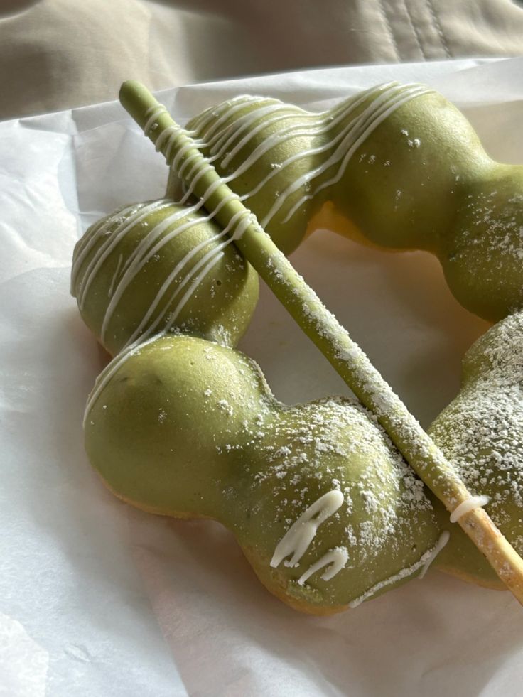 some green apples with white icing on them and one has a stick in it