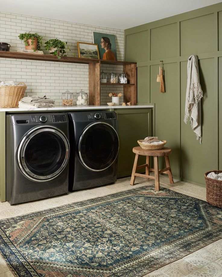 a washer and dryer in a small room with green walls, rugs and shelves