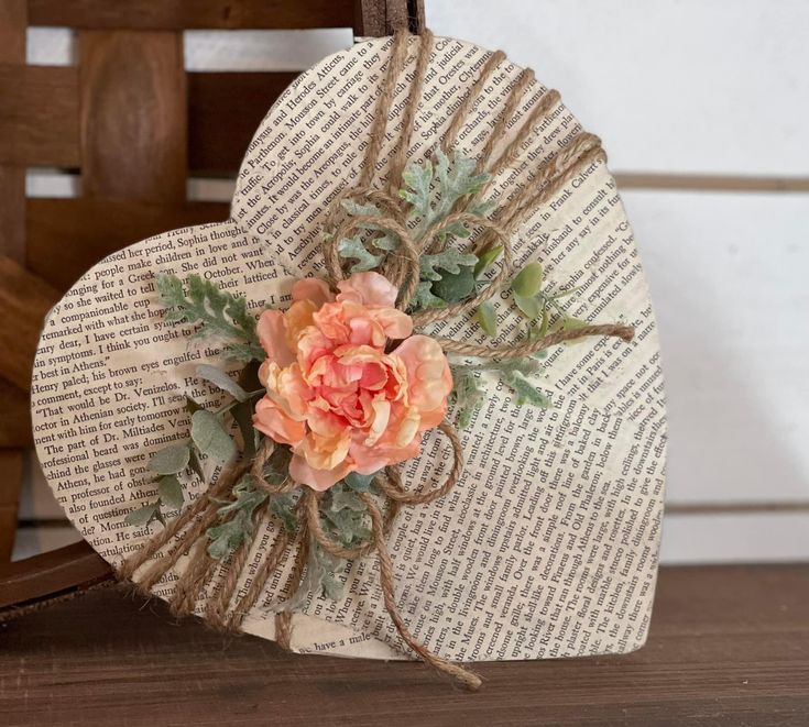 a paper heart with flowers on it sitting on top of a wooden table next to a chair