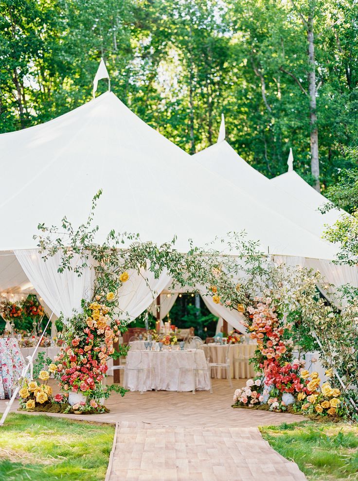 a white tent with tables and chairs set up for an outdoor wedding reception in the woods