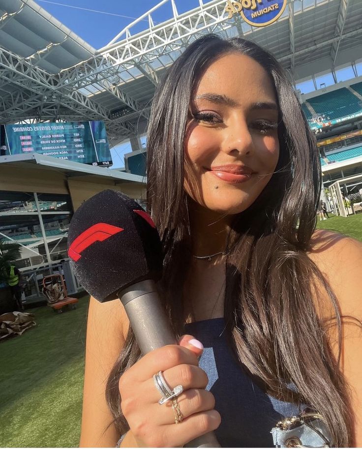 a woman holding a microphone in front of a stadium