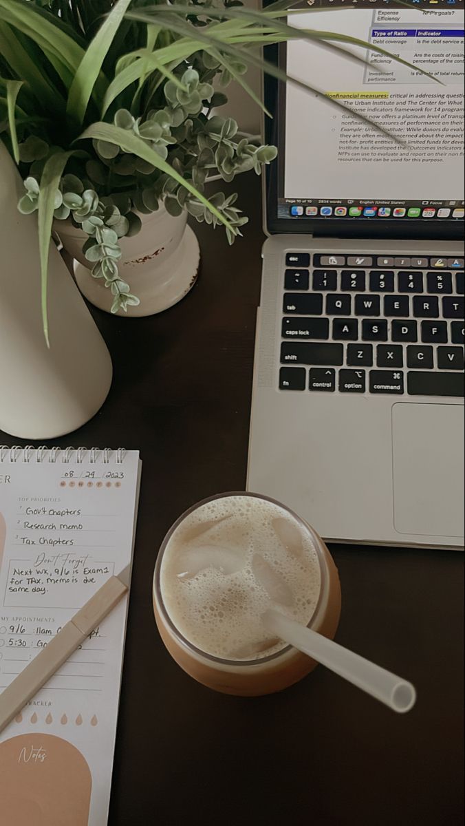 an open laptop computer sitting on top of a desk next to a cup of coffee