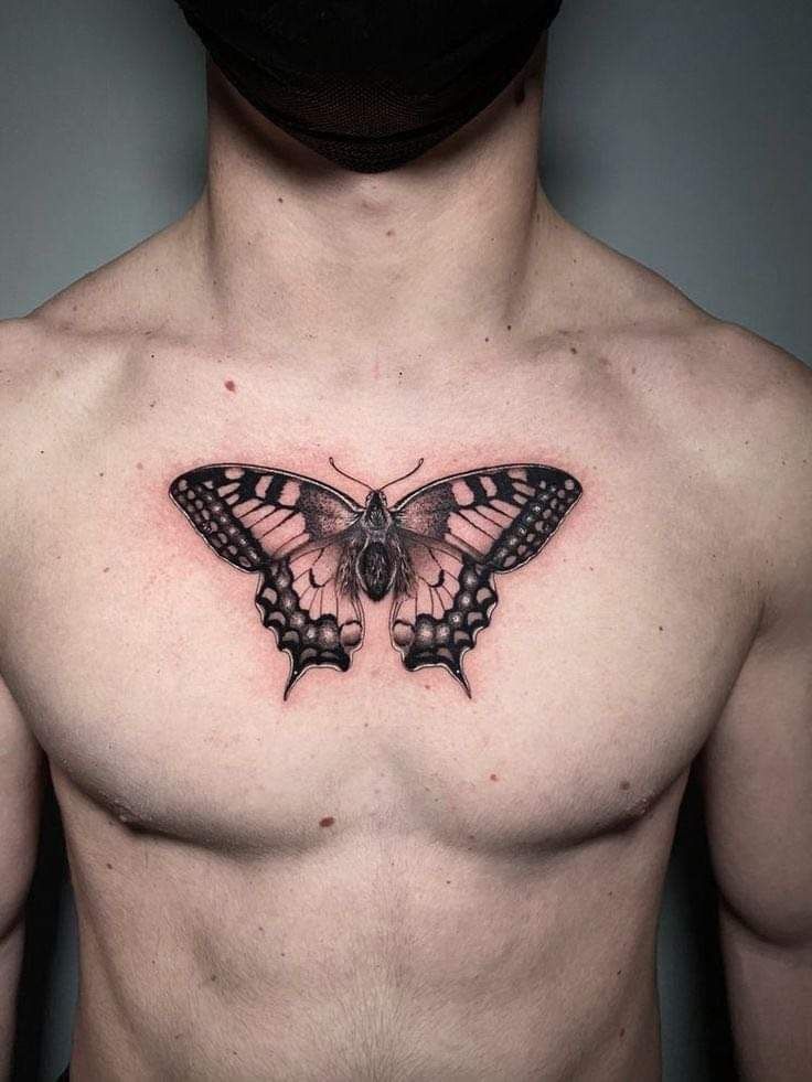 a man's chest with a butterfly tattoo on the top and bottom part of his chest