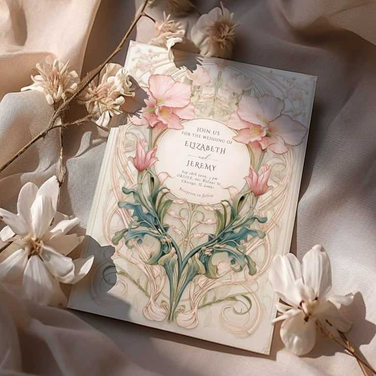 the wedding card is surrounded by flowers and satin fabric on top of it, with an elegant design