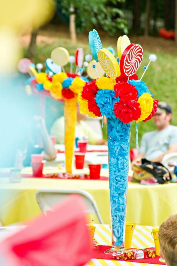 a group of people sitting around a table with candy and flowers in vases on it