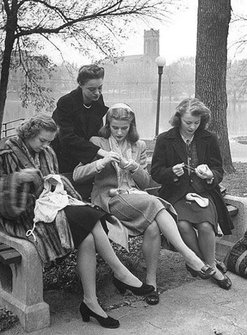 an old black and white photo of people sitting on the ground in front of a crowd