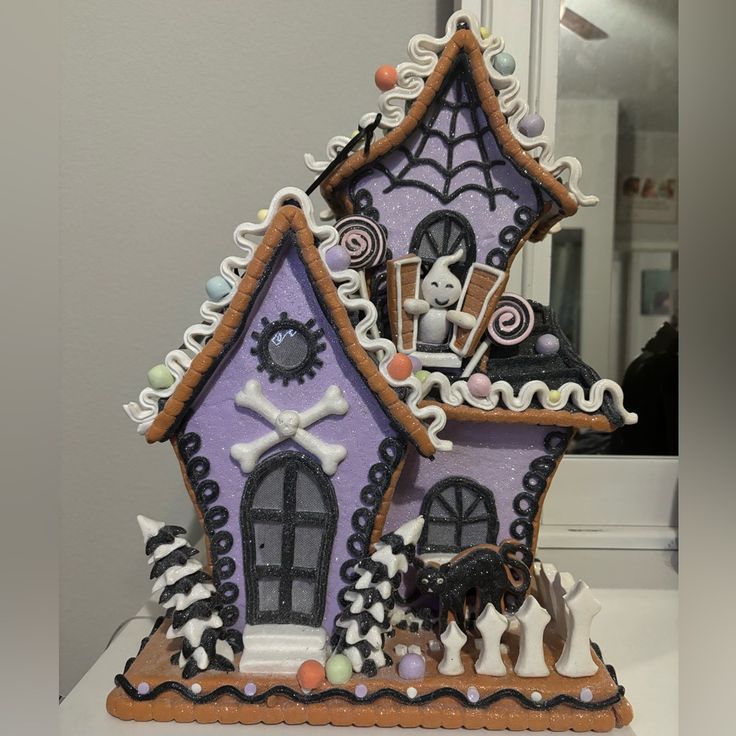 a purple and white gingerbread house decorated with halloween decorations on the front, along with black and white dog figurines