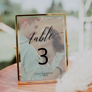 a table number frame with a couple kissing in the middle and text underneath it that says table 3