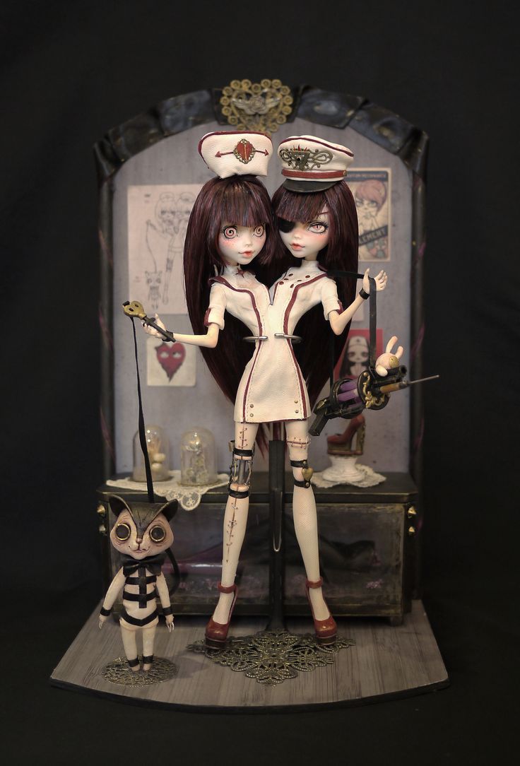 two dolls standing next to each other in front of a black background with an owl