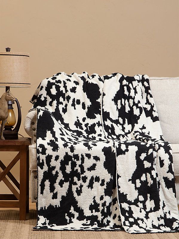 a black and white blanket sitting on top of a couch next to a table with a lamp