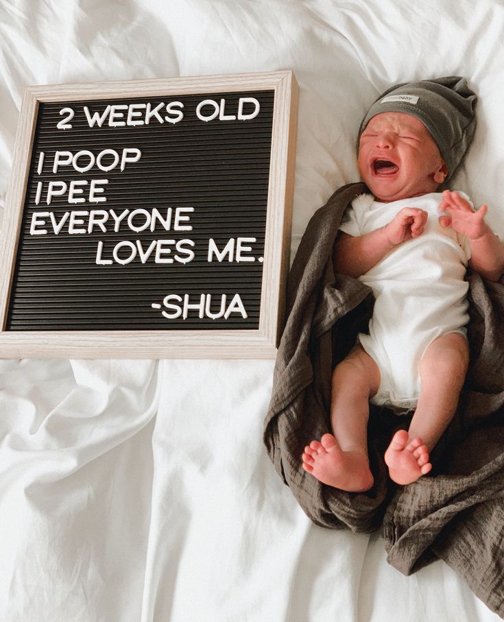 a baby laying on top of a bed next to a sign