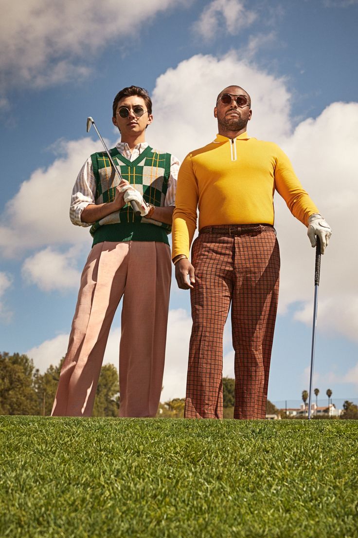 two men standing next to each other on top of a green grass covered golf course