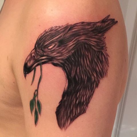 an eagle with a flower in it's beak is shown on the back of a woman's shoulder