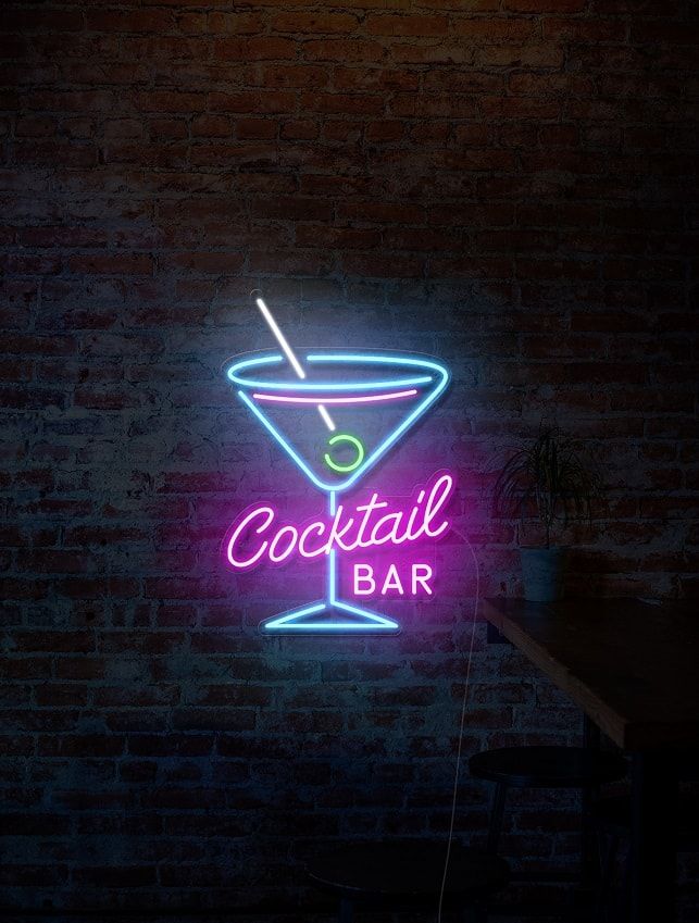 a neon sign that says cocktail bar in front of a brick wall with a drink glass on it