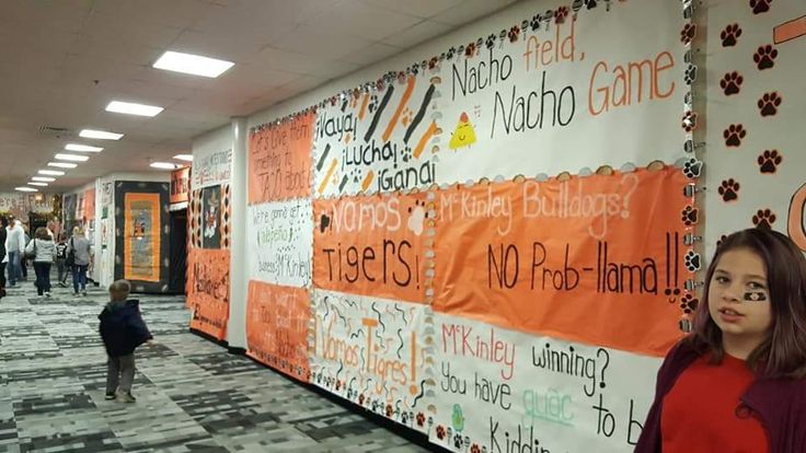 a woman standing next to a wall covered in orange and white signs with words on it