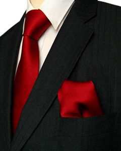 a man wearing a black suit with a red tie and pocket square on his lapel