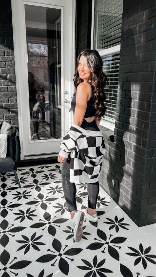 a woman standing in front of a black and white tile floor