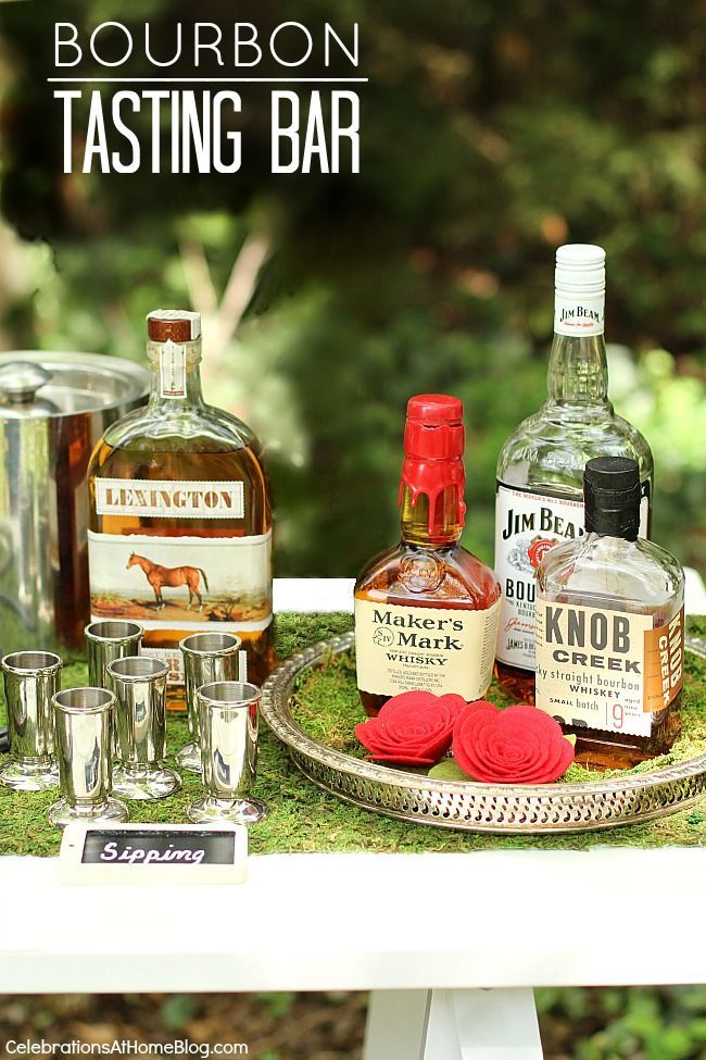 bottles and glasses are sitting on a tray with moss growing around it, along with shot glasses