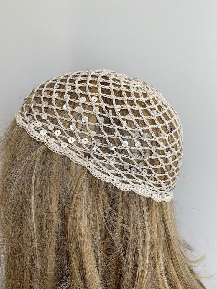 a woman's head wearing a white netted hat with buttons on the side