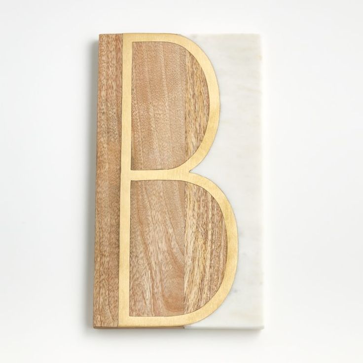 the letter b is made out of wood and has a white marble base with gold trim