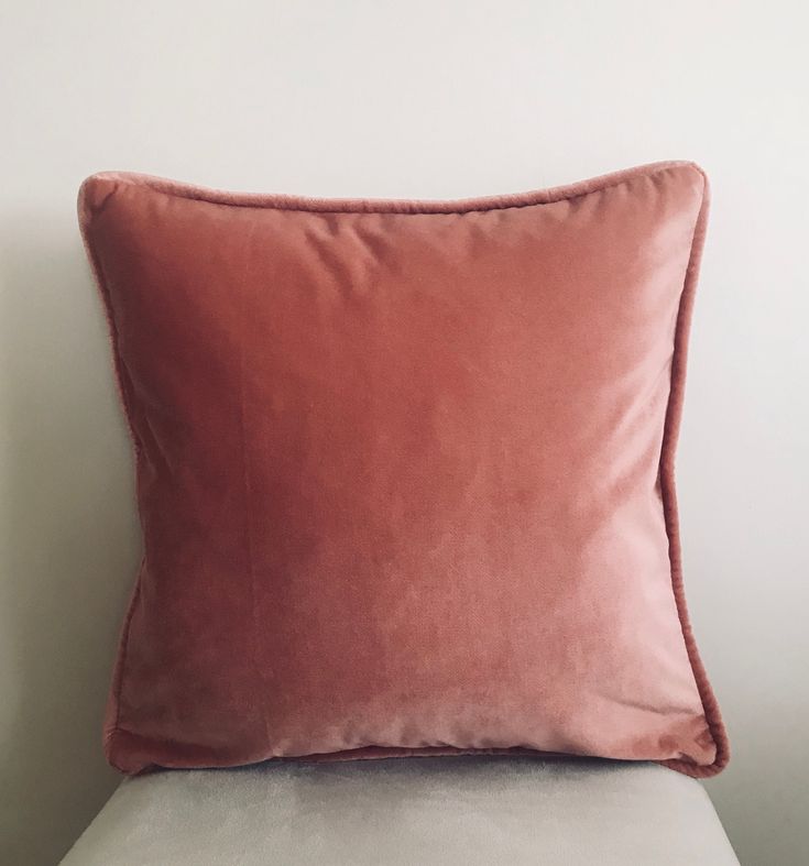 a pink pillow sitting on top of a white couch