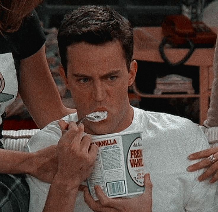 a man is brushing his teeth while holding a box of ice cream in his hand