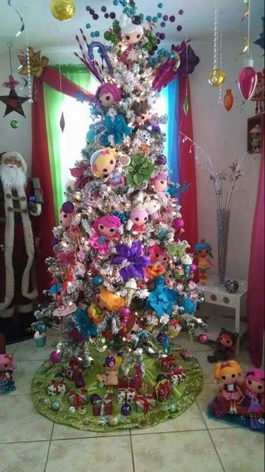 a brightly colored christmas tree with lots of ornaments and decorations on the top, sitting in front of a window