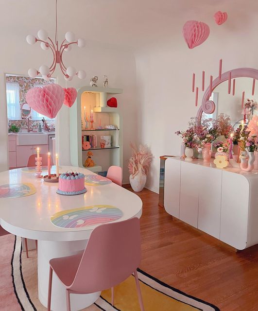 a dining room table with pink chairs and decorations