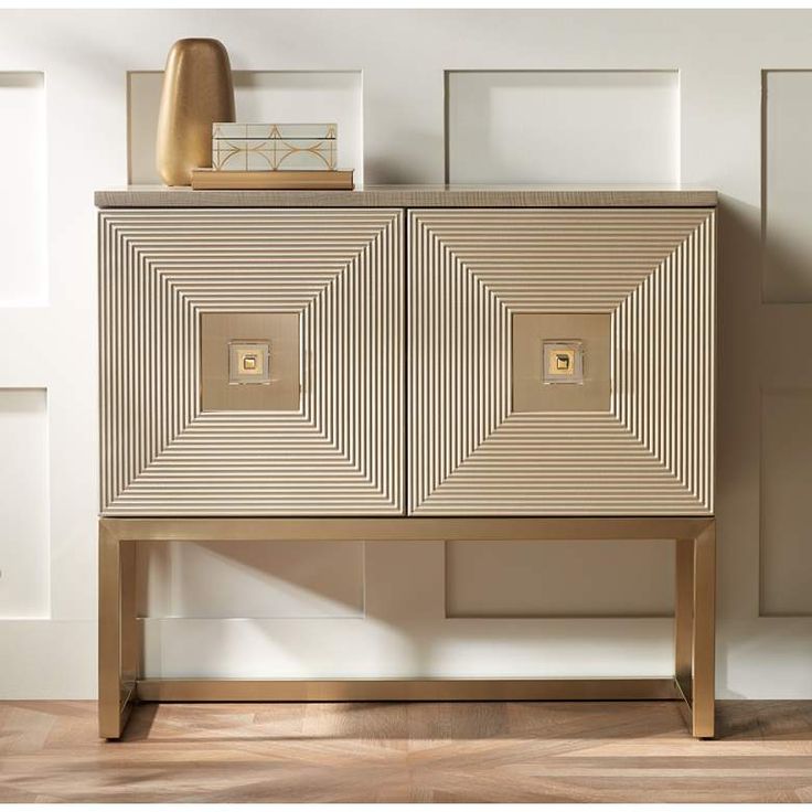 a white and gold cabinet in a room with wood flooring next to a lamp