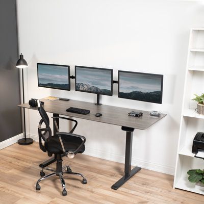 a desk with three computer monitors and a chair in front of it on top of a hard wood floor