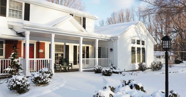 a white house covered in snow next to a lamp post and trees with no leaves