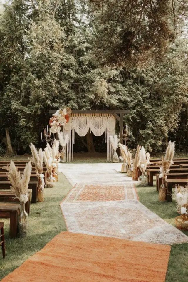 an outdoor ceremony setup with white and orange flowers on the aisle, decorated with pamodia