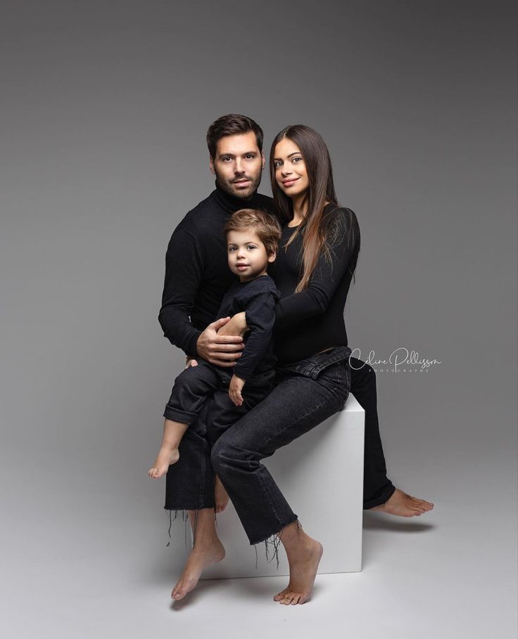 a man, woman and child are sitting on a white box with their arms around each other