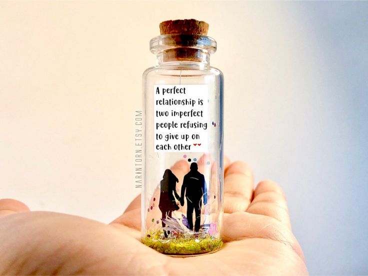 a person holding a tiny glass bottle with a message on the inside that says, a great relationship is not imperfecting people missing to go on each other